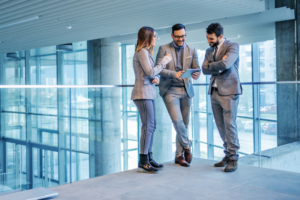 Group of successful real estate agents standing in building in construction process and looking at tablet.